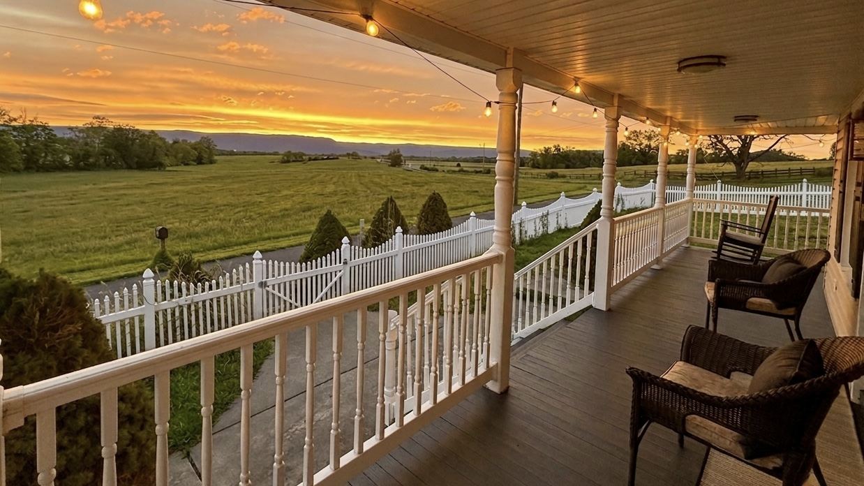 Wraparound porch overlooking farm fields at sunset